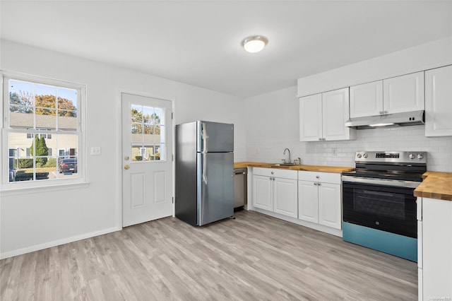 kitchen featuring wood counters, light wood-type flooring, decorative backsplash, white cabinets, and appliances with stainless steel finishes