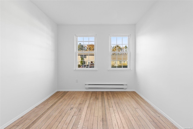 empty room with baseboard heating and light hardwood / wood-style floors