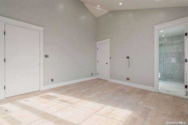 spare room with light wood-type flooring and high vaulted ceiling