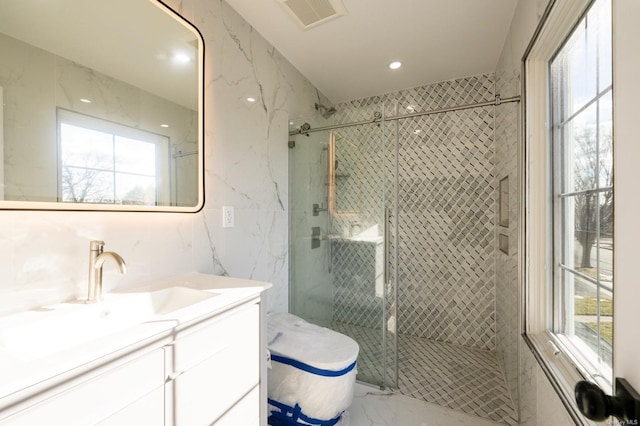 bathroom with a shower with shower door, vanity, and a wealth of natural light