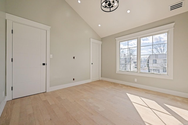 spare room featuring high vaulted ceiling and light hardwood / wood-style floors