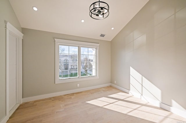 spare room featuring light wood-type flooring and lofted ceiling