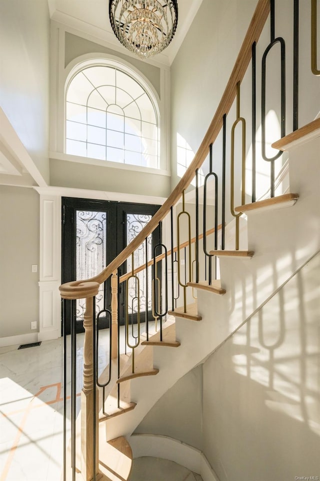 foyer featuring an inviting chandelier, plenty of natural light, and a towering ceiling