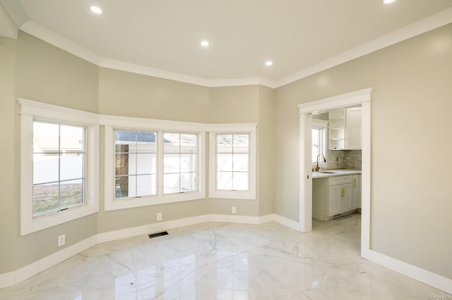 unfurnished room featuring sink, crown molding, and a healthy amount of sunlight