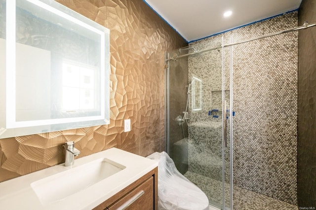 bathroom with tile walls, vanity, a shower with door, and toilet