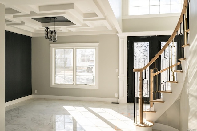 entryway featuring coffered ceiling, a high ceiling, a chandelier, and a healthy amount of sunlight