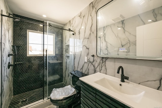 bathroom with a shower with shower door, vanity, tile walls, and toilet