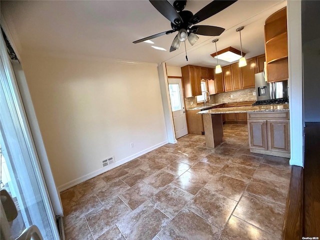 kitchen with backsplash, light stone counters, ceiling fan, sink, and decorative light fixtures