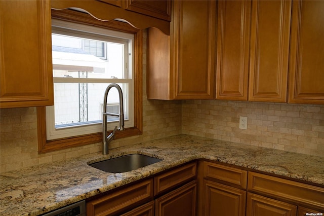 kitchen with decorative backsplash, light stone countertops, sink, and stainless steel dishwasher