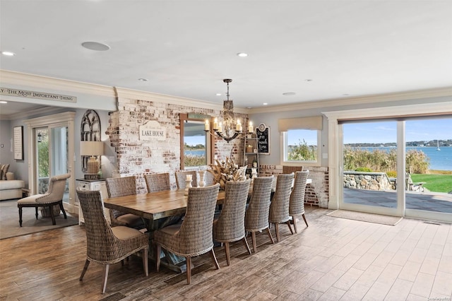 dining area featuring a water view, a notable chandelier, crown molding, and hardwood / wood-style floors