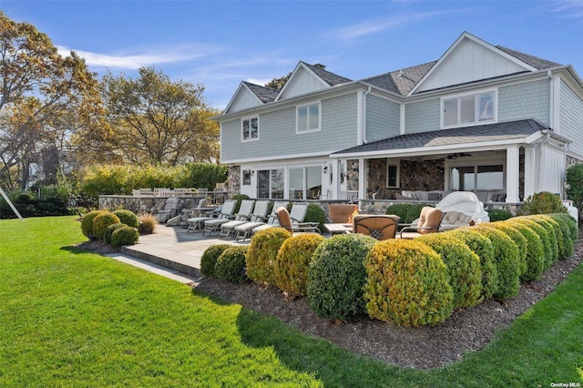rear view of property with a lawn, an outdoor living space, and a patio