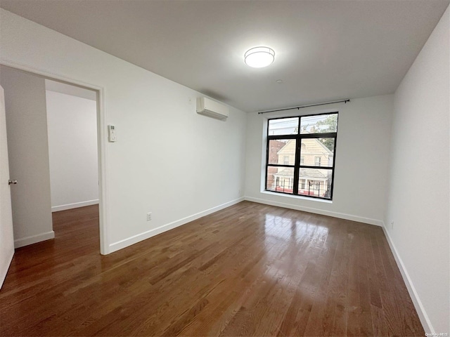 spare room featuring a wall mounted air conditioner and dark wood-type flooring