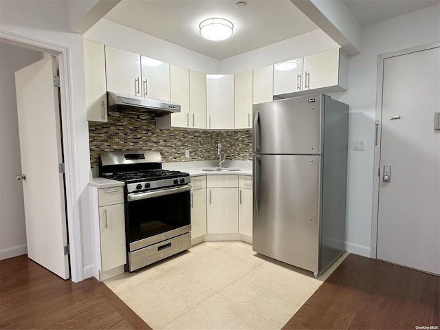 kitchen with backsplash, light hardwood / wood-style flooring, stainless steel appliances, and sink