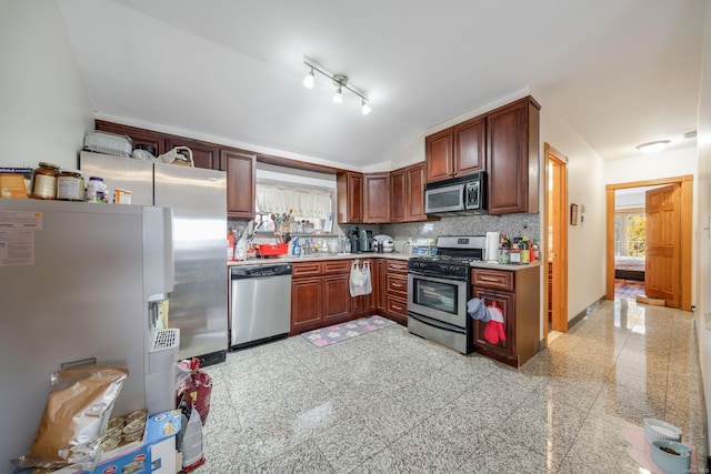 kitchen featuring backsplash, stainless steel appliances, vaulted ceiling, and sink