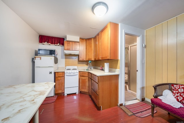 kitchen featuring dark hardwood / wood-style flooring, white appliances, and sink