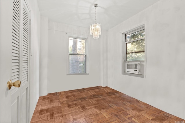 unfurnished room with dark parquet floors, an inviting chandelier, plenty of natural light, and cooling unit