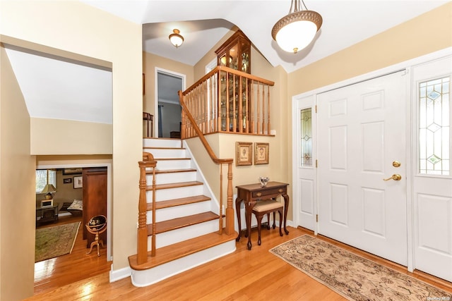 foyer featuring wood-type flooring and vaulted ceiling