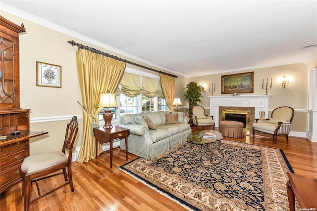 living room with hardwood / wood-style flooring, ornamental molding, and a fireplace