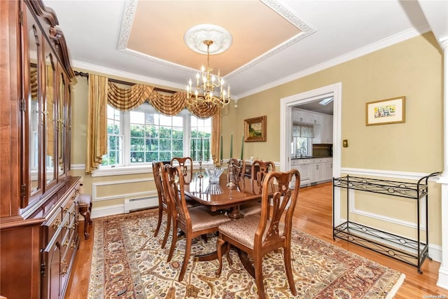 dining room featuring a chandelier, crown molding, sink, and light hardwood / wood-style floors