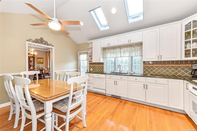 kitchen featuring white cabinets, decorative backsplash, light hardwood / wood-style flooring, and vaulted ceiling with skylight