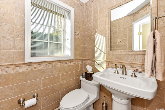 bathroom with toilet, tile walls, and sink