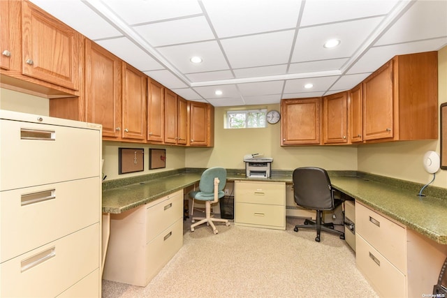 office space with a paneled ceiling and built in desk