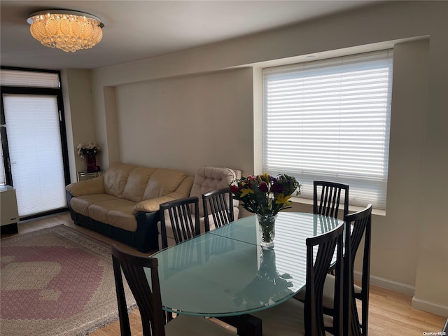 dining area with light hardwood / wood-style floors and an inviting chandelier