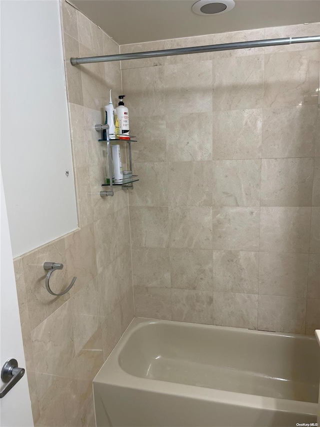 bathroom with tiled shower / bath and tile walls