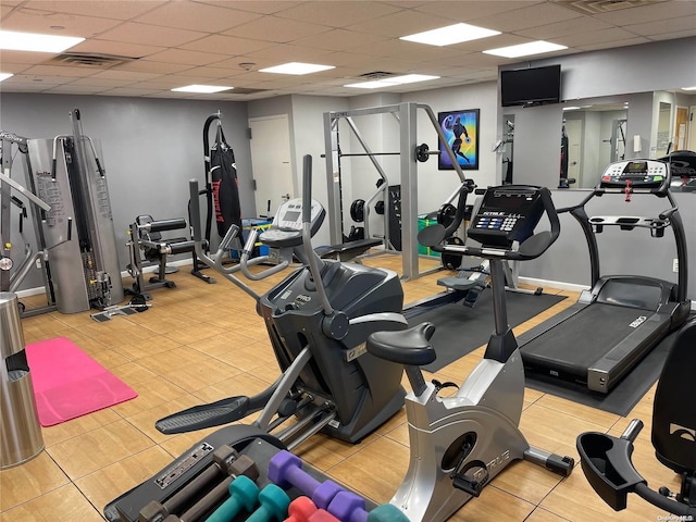 workout area featuring a drop ceiling and light tile patterned floors