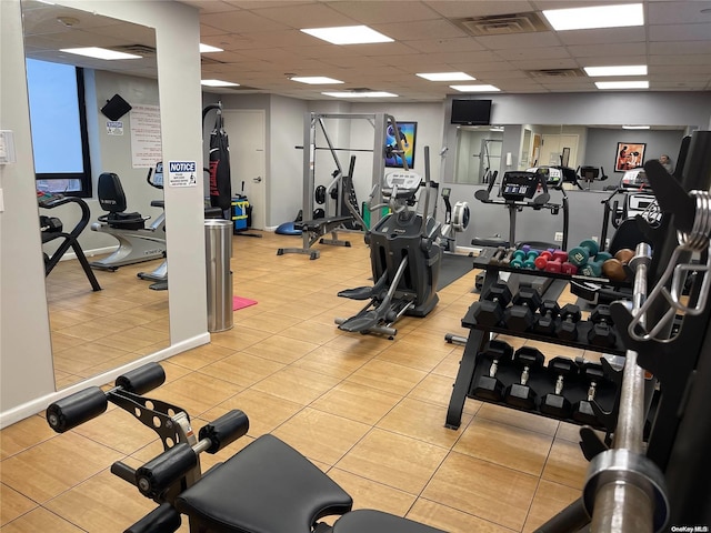 exercise room with a paneled ceiling and light tile patterned floors