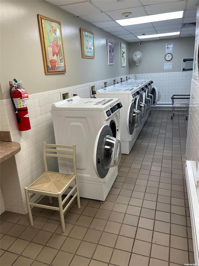 laundry area with tile patterned floors, washer and clothes dryer, and tile walls