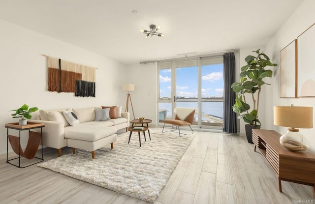 living room featuring a water view, light hardwood / wood-style flooring, and expansive windows