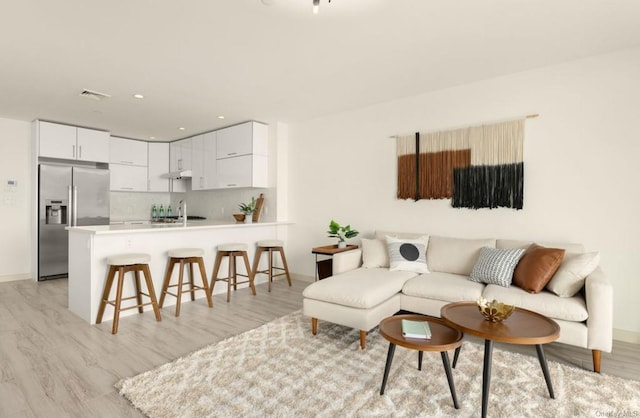 living room featuring sink and light hardwood / wood-style flooring