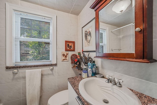 bathroom with vanity, toilet, and tile walls