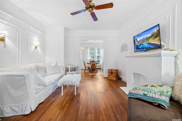 living room featuring ceiling fan, a fireplace, dark wood-type flooring, and radiator