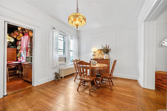 dining room featuring a chandelier, radiator heating unit, and wood-type flooring