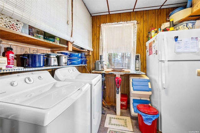 washroom featuring carpet flooring, washing machine and clothes dryer, wooden walls, and cabinets