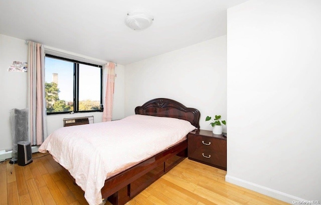 bedroom with an AC wall unit and light hardwood / wood-style flooring