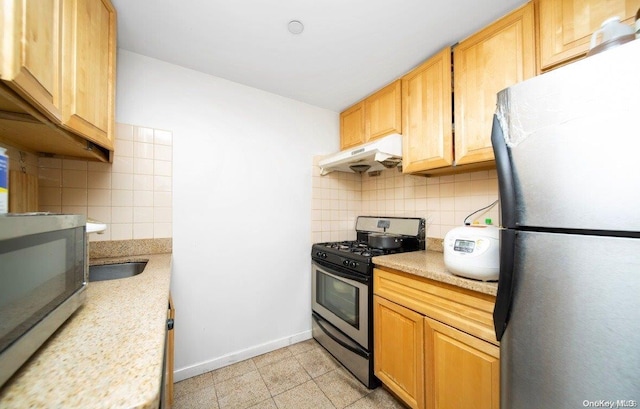 kitchen with backsplash, sink, light tile patterned floors, and appliances with stainless steel finishes