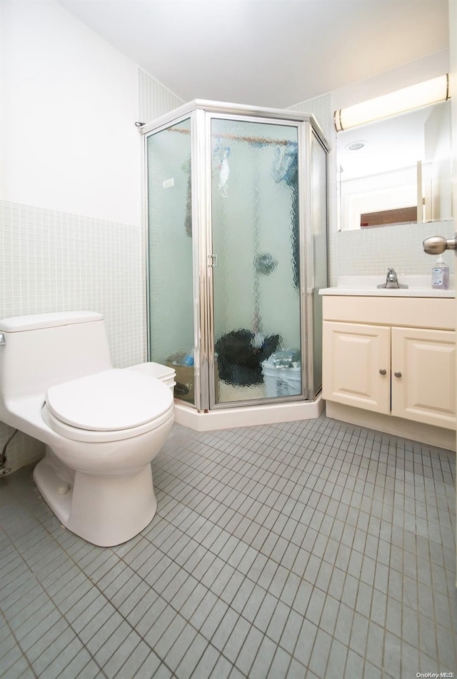 bathroom featuring a shower with door, vanity, tile walls, and toilet