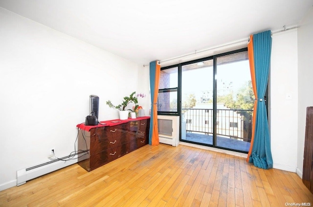 spare room featuring a wall of windows, wood-type flooring, and a baseboard radiator