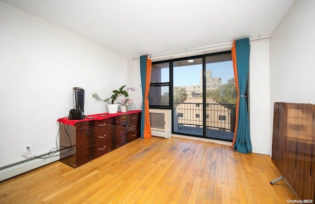 interior space featuring hardwood / wood-style flooring, baseboard heating, and floor to ceiling windows