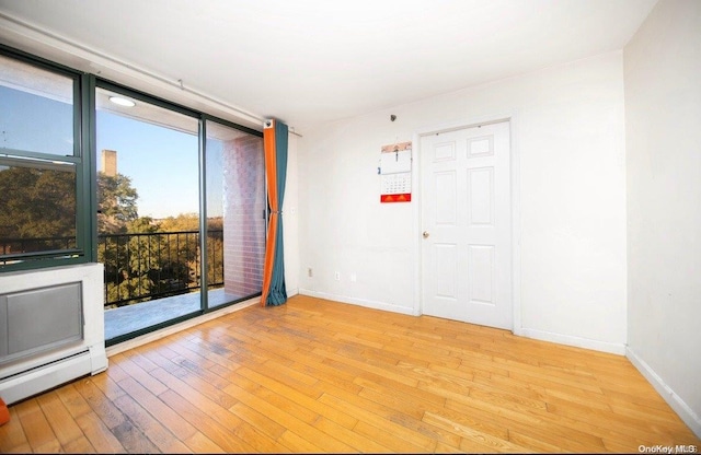 136-16 35th Ave Unit 7C, Flushing, NY 11354 - spare room featuring wood-type flooring and baseboard heating