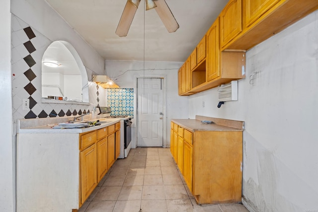 kitchen with white range, sink, ceiling fan, light tile patterned floors, and tasteful backsplash