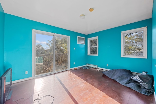 unfurnished room with wood-type flooring, plenty of natural light, and a baseboard heating unit