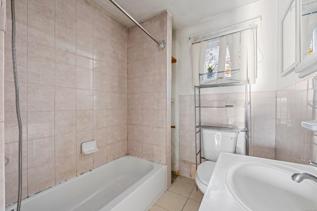 full bathroom featuring tiled shower / bath, sink, tile patterned flooring, toilet, and tile walls