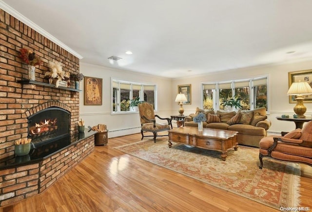 living room featuring a brick fireplace, a baseboard heating unit, and light hardwood / wood-style flooring