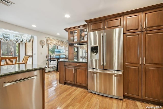 kitchen with dark stone countertops, light hardwood / wood-style flooring, and stainless steel appliances