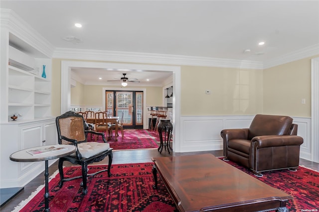 living room with ceiling fan, built in features, a wall unit AC, crown molding, and wood-type flooring