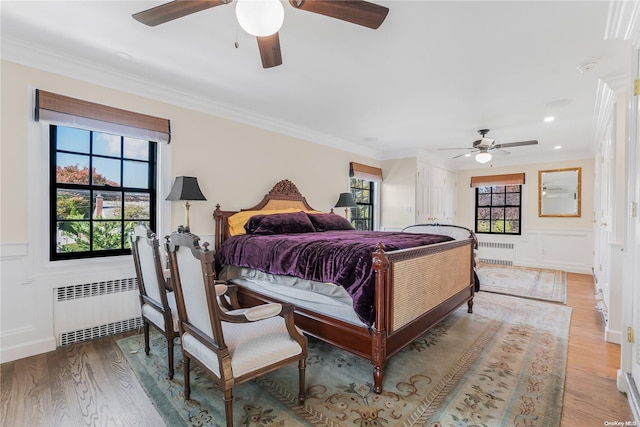 bedroom featuring ceiling fan, radiator heating unit, and light wood-type flooring